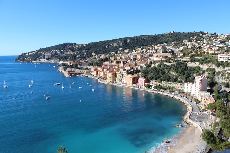 Stunning aerial view of Villefranche-sur-Mer with coastline and boats on a clear summer day.